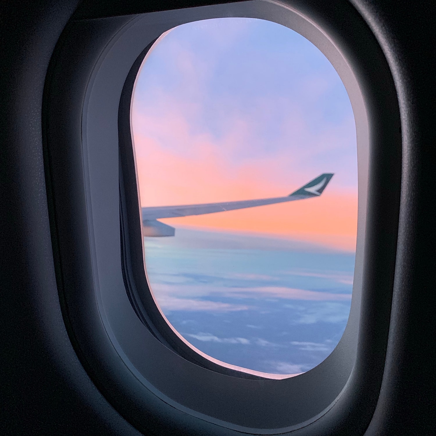 Airplane window view with sunset and wing.