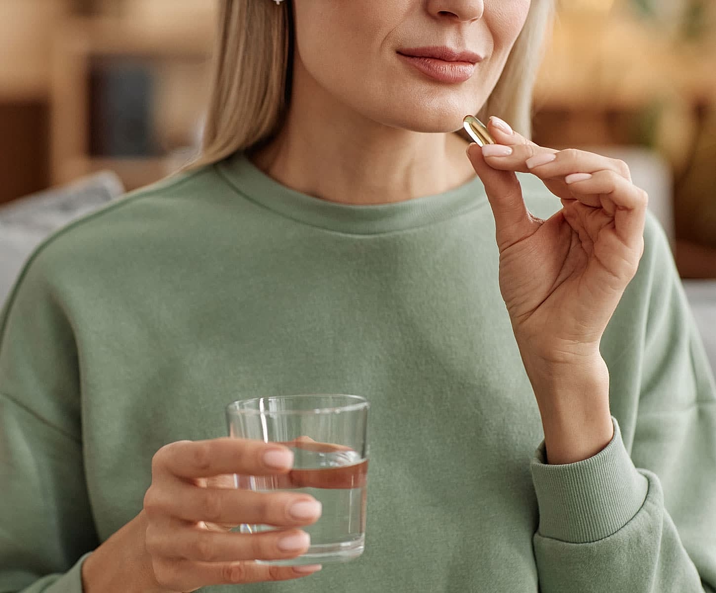 Woman taking a supplement with a glass of water.